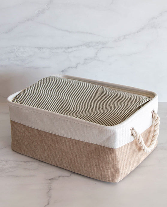 Beige and white storage basket made from linen with a cotton rope handle with sheets inside
