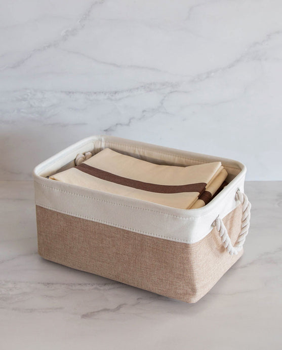 Beige and white storage basket made from linen with a cotton rope handle with pillowcases inside 