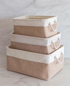 Set of three beige and white storage baskets made from linen with a cotton rope handle, in sizes small, medium and large 