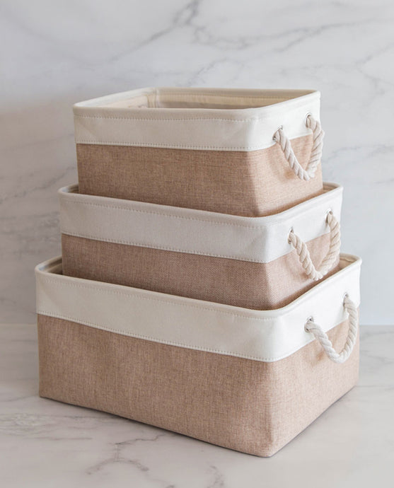 Set of three beige and white storage baskets made from linen with a cotton rope handle, in sizes small, medium and large 