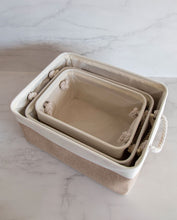 Load image into Gallery viewer, Set of three beige and white storage baskets made from linen with a cotton rope handle, in sizes small, medium and large 