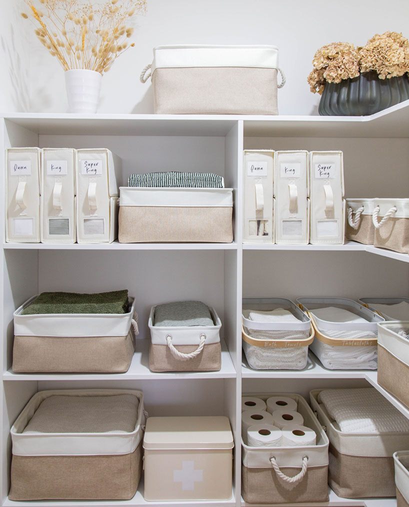 Neutral beige linen storage bins arranged neatly on white shelves