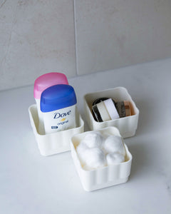 White bathroom container designed to fit in bathroom drawers and store cotton balls, hair ties and hair clips