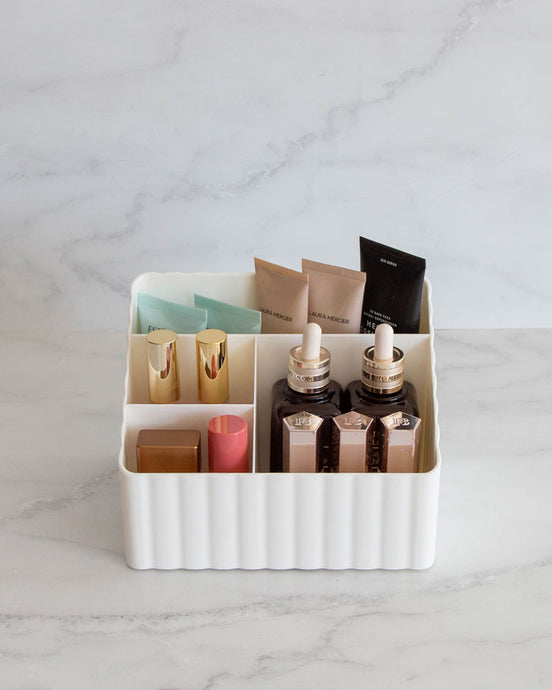 Tiered off white container with two small and two large compartments, used to store toiletries, stationary, or under sink items