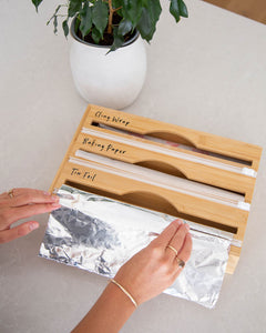 Bamboo food wrap dispenser with three slots allowing you to hold cling wrap, tin foil, and baking paper in one place