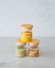 Load image into Gallery viewer, Glass and bamboo herb and spice jars used to store packets of herbs and spices in the kitchen
