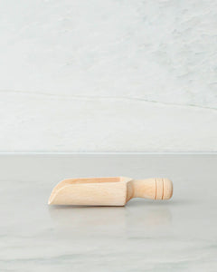 Wooden scoop with handle used to scoop ingredients such as flour and sugar from a jar
